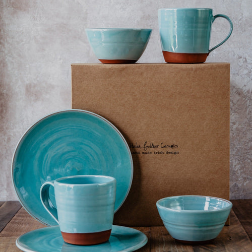 Breakfast set for 2 people, turquoise pottery in front of a brown gift box.
