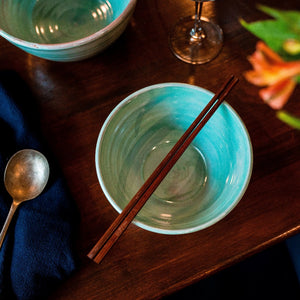 Turquoise bowl with chopsticks from above on a dark wooden table.