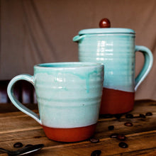 Load image into Gallery viewer, Large turquoise mug and cafetiere on a wooden board with coffee beans scattered around.
