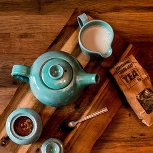 Turquoise Teapot, milk jug and sugar bowl from above on a wooden board.