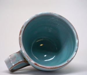 Turquoise espresso cup on it's side on a white background